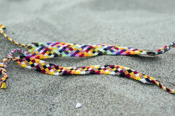 Natural bracelets of friendship in a row, colorful woven friendship bracelets, background, rainbow colors, checkered pattern, in the sand on the beach