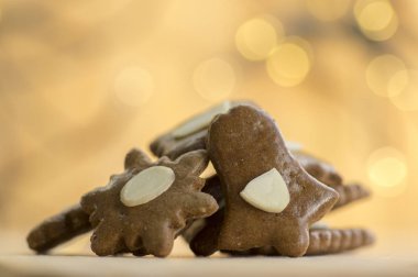 Dilimlenmiş badem, Noel kurabiyeleri, arka plan, çan ve kar tanesi yıldız şekilleri üzerine Noel ışıkları düşünceler ile kahverengi Moravyalı karanlık gingerbreads