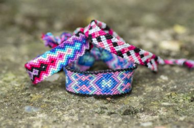 Üç el yapımı ev yapımı renkli doğal dokuma gri taş arka plan üzerinde ayrıntı görünümü izole dostluk bilezik