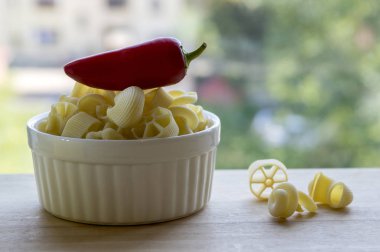 Çeşitli ahşap masa ve olgunlaşmış kırmızı jalapeno biber beyaz fırın kapta makarna karışımı