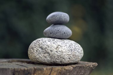 Three zen stones pile on wooden stump, white and grey meditation pebbles tower clipart