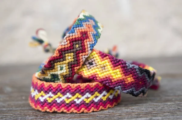 Üç basit el yapımı ev yapımı doğal dokuma dostluk bilezik ahşap arka plan, gökkuşağı renkleri, Damalı deseni