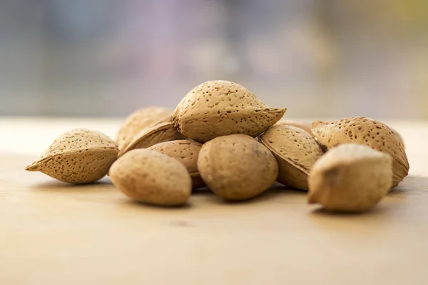 Almonds in hard shells, pile on wooden table