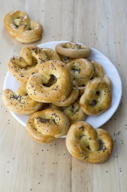 Fırında taze simit beyaz tabak, kalp ve bükülmüş düğüm şekilleri, haşhaş tohumu tuz ve kimyon tohumu ile kaplı