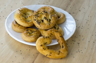 Fırında taze simit beyaz tabak, kalp ve bükülmüş düğüm şekilleri, haşhaş tohumu tuz ve kimyon tohumu ile kaplı
