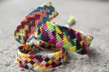 Üç basit el yapımı ev yapımı doğal dokuma dostluk bilezik gri beton arka plan, gökkuşağı renkleri, Damalı deseni