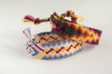 İki basit el yapımı ev yapımı doğal dokuma dostluk bilezik beyaz arka plan, gökkuşağı renkleri, Damalı deseni