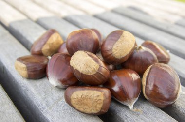 Ahşap bir masa üzerinde lezzetli ve sağlıklı kahverengi fındık ham tatlı kestaneler dağınık