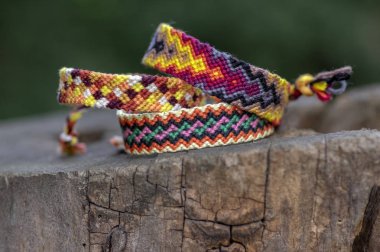 Üç el yapımı ev yapımı renkli doğal dokuma ışığında ahşap güdük üzerinde izole dostluk bilezik