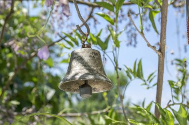 Küçük metalik oryantal çan Bahçe, güneşli gün, yeşil etrafında asılı