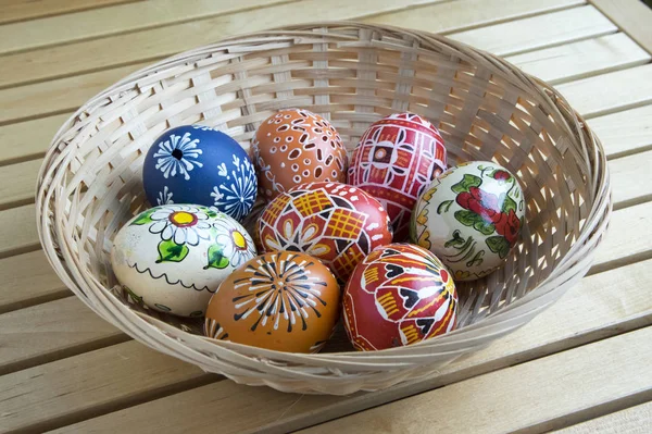 Homemade handmade painted eggs in the basket, Easter decoration on the table, small wooden flower