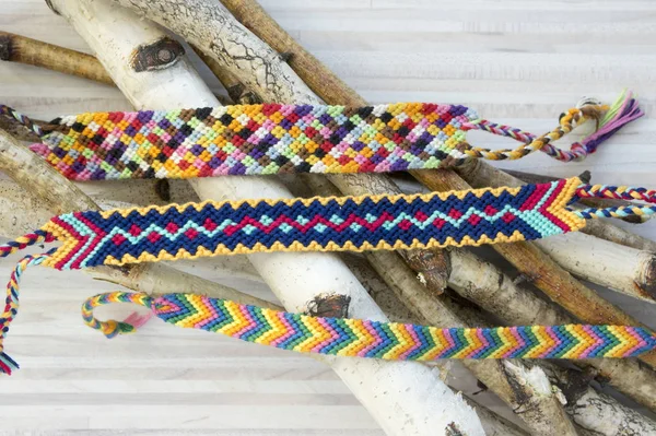 Natural bracelets of friendship in a row, colorful woven friendship bracelets, background, rainbow colors, checkered pattern, birch branches on background