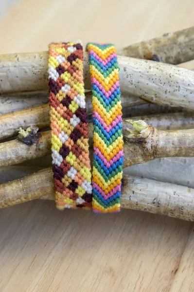 Natural bracelets of friendship in a row, colorful woven friendship bracelets, background, rainbow colors, checkered pattern, birch branches on background