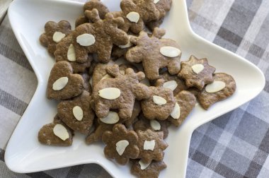Kahverengi Moravyalı karanlık gingerbreads dilimlenmiş badem, Noel kurabiyeleri, beyaz yıldız şekli plaka üzerinde ren geyiği şekiller, tek tek grup