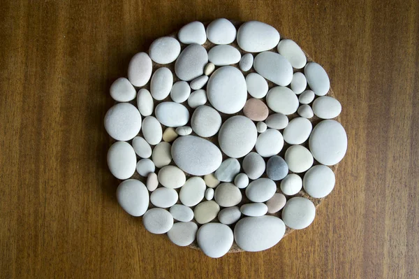 Magic stone circle shape on dark wooden background, light pebbles, mandala made of stones
