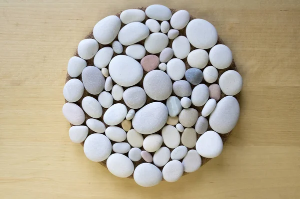 Magic stone circle shape on birch wooden background, light pebbles, mandala made of stones