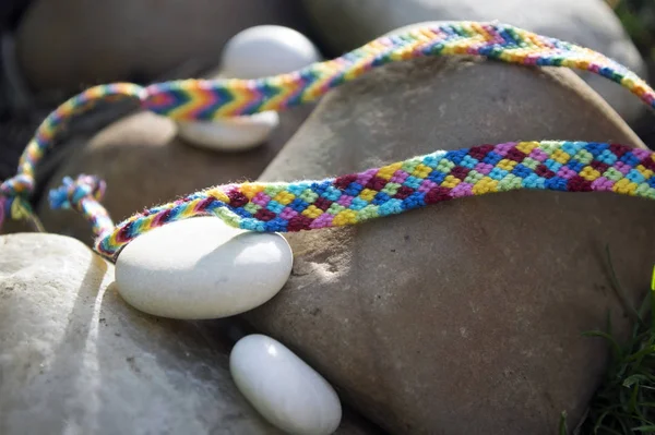 Natural bracelets of friendship in a row, colorful woven friendship bracelets, background, rainbow colors, checkered pattern, white pebbles