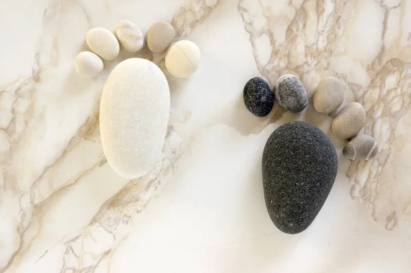 Two tiny stone feet and ten toes on wooden background, black and white, stone in the shape of a human children feet