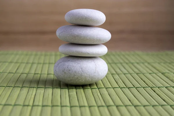 和谐与平衡 绿色竹草垫上的稳重石 石刻雕塑 白色鹅卵石 — 图库照片