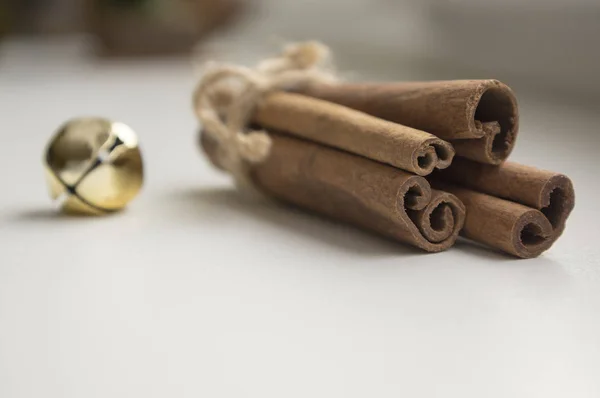 Fresh raw cinnamon sticks on wooden table tied with natural twine and jingle bells
