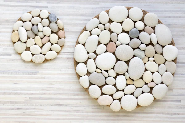 Magic stone circles shapes on light wooden background, light pebbles, mandala made of stones