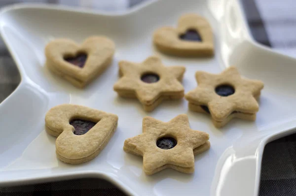Christmas sweets and cookies made from shortcrust pastry, various shapes filled with marmalade and decorated with chocolate, star shaped plate