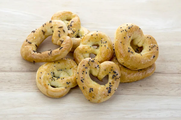 Havlu, kalp ve bükülmüş düğüm şekilleri, ahşap masa üzerinde pişmiş taze simit haşhaş tohumu tuz ve kimyon tohumu ile kaplı