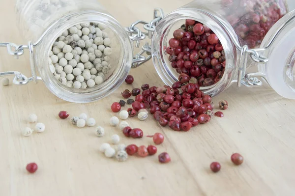 Piper nigrum fruit, white pepper and Schinus molle, American false pink pepper, spilled on the wooden table