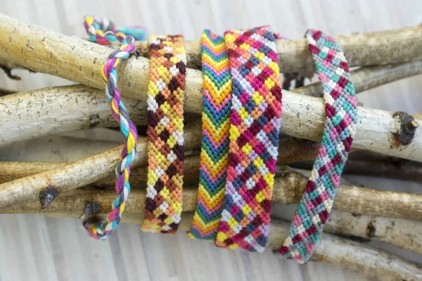 Natural bracelets of friendship in a row, colorful woven friendship bracelets, background, rainbow colors, checkered pattern, birch branches on background