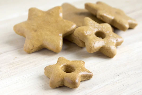 Light brown gingerbreads on wooden mat, Christmas cookies, shapes, stars