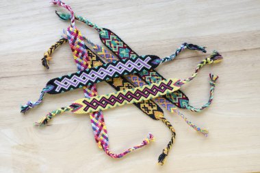 El yapımı ev yapımı renkli doğal dokuma dostluk bilezik ahşap masa, moda aksesuar grubu, çeşitli renkler üzerinde Grup