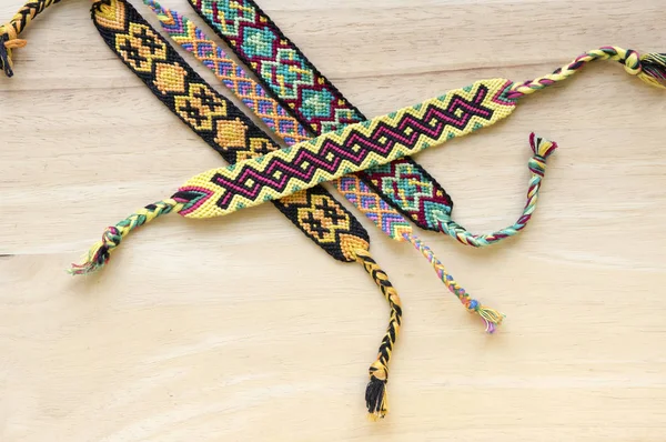 El yapımı ev yapımı renkli doğal dokuma dostluk bilezik ahşap masa, moda aksesuar grubu, çeşitli renkler üzerinde Grup