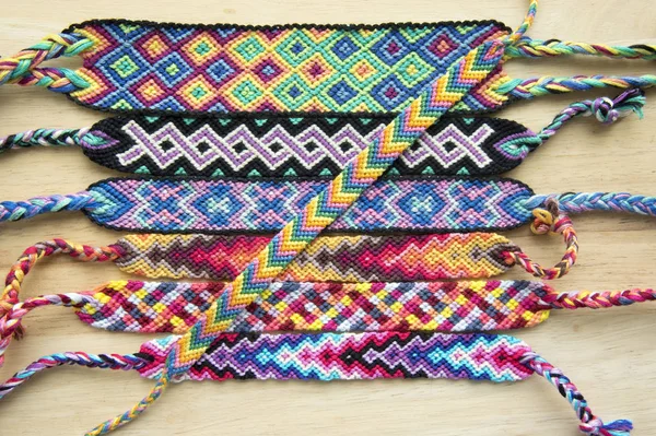 El yapımı ev yapımı renkli doğal dokuma dostluk bilezik ahşap masa, moda aksesuar grubu, çeşitli renkler üzerinde Grup