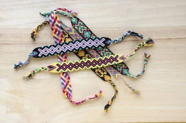 El yapımı ev yapımı renkli doğal dokuma dostluk bilezik ahşap masa, moda aksesuar grubu, çeşitli renkler üzerinde Grup