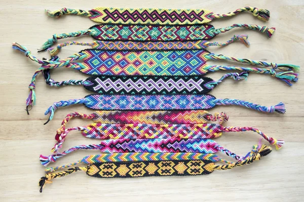 El yapımı ev yapımı renkli doğal dokuma dostluk bilezik ahşap masa, moda aksesuar grubu, çeşitli renkler üzerinde Grup