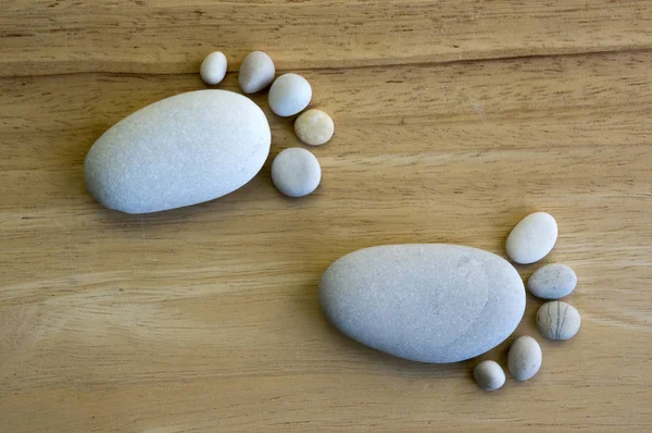 Two tiny stone feet and ten toes on wooden background, stone in the shape of a human feet, birth announcement