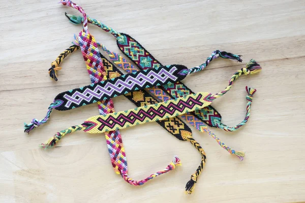 El yapımı ev yapımı renkli doğal dokuma dostluk bilezik ahşap masa, moda aksesuar grubu, çeşitli renkler üzerinde Grup