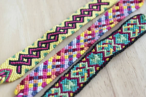 El yapımı ev yapımı renkli doğal dokuma dostluk bilezik ahşap masa, moda aksesuar grubu, çeşitli renkler üzerinde Grup