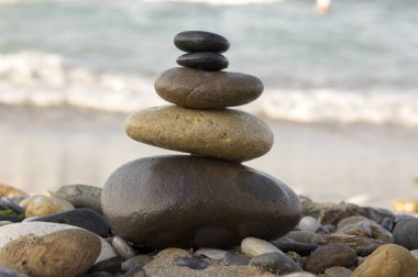 Uyum ve denge, deniz, rock zen heykel, güneşli bir gün karşı dengeli kahverengi ve siyah taşlar