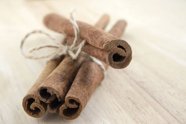 Fresh raw cinnamon sticks on wooden table tied with natural twine