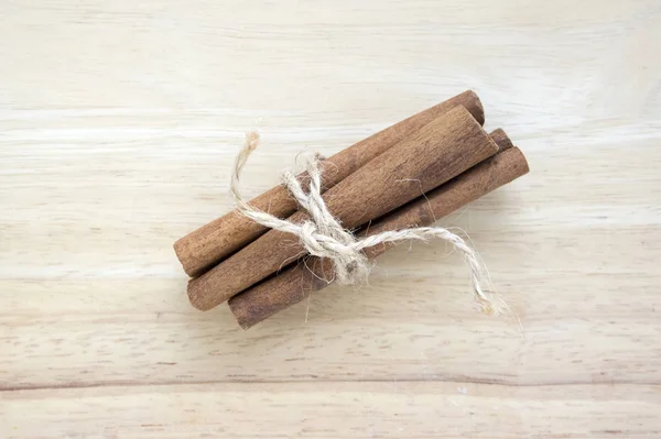 Fresh raw cinnamon sticks on wooden table tied with natural twine