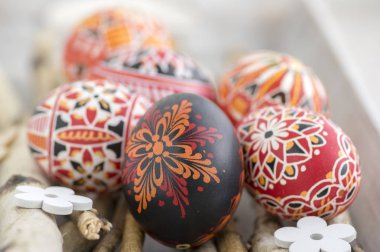 Ev yapımı el yapımı Boyalı Paskalya yumurtaları huş ağacı dalları gri ahşap tepsi, geleneksel hnadcraft renkli yumurta, beyaz dekoratif ahşap çiçek üzerinde