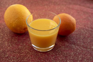 Tablo, kırmızı arka planda, çok lezzetli ve sağlıklı iki turuncu meyveler ile taze portakal suyu