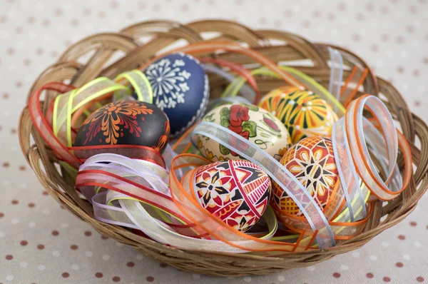 Coloridos huevos de Pascua pintados en canasta de mimbre marrón cubierta con cintas de colores, naturaleza muerta tradicional de Pascua — Foto de Stock