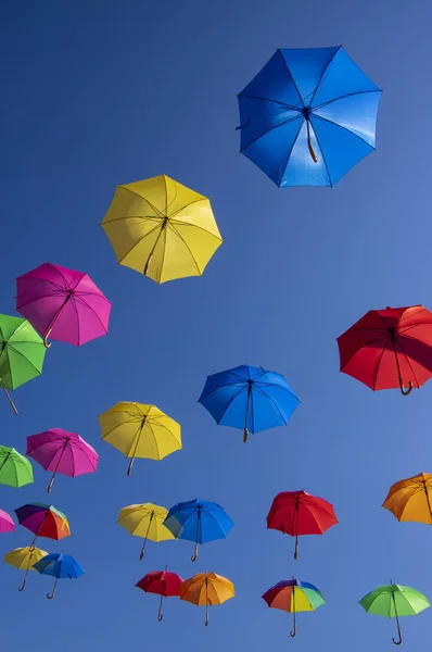 Group of flying umbrellas isolated on blue background, ready for the rain, wallpaper background, bright various colors