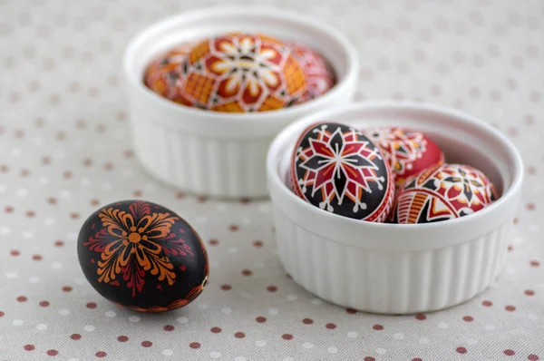 Coloridos huevos de Pascua pintados en cuencos blancos en mantel punteado, tradicional hermosa naturaleza muerta de Pascua — Foto de Stock