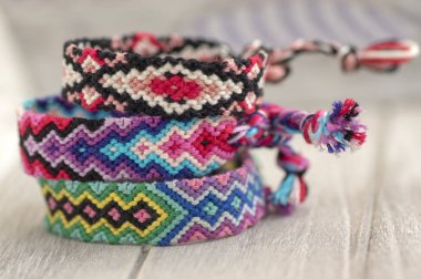 Ahşap arka plan, gökkuşağı renkleri, damalı desen üzerinde dostluk üç renkli el yapımı doğal dokuma bilezik