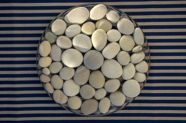 Kruh složený z bílých a šedých kamenů, oblázků mandalových pozadí na modrém bílém proužkované pozadí za denního světla, koncepce života — Stock fotografie