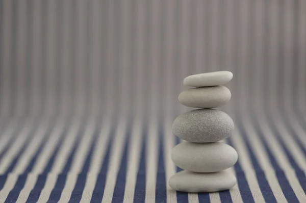 Harmonia e equilíbrio, pebble rock cairn, pedras de equilíbrio simples sobre fundo listrado branco e azul, escultura zen rocha, uma torre — Fotografia de Stock