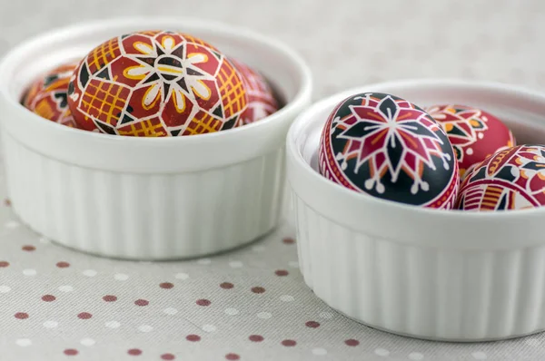 Coloridos huevos de Pascua pintados en cuencos blancos en mantel punteado, tradicional hermosa naturaleza muerta de Pascua — Foto de Stock